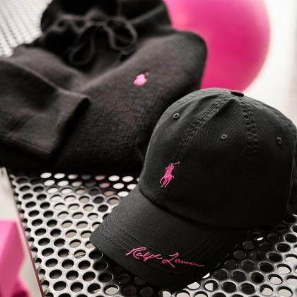 A selection of bacl clothing, including a jumper and a cap. They both have a pink version of the Ralph Lauren logo on them.