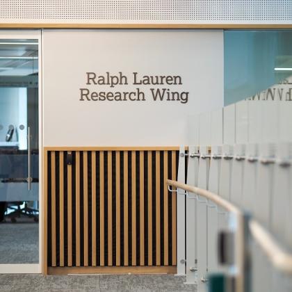 Inside of the Oak Cancer Centre, there is a glass door at the end of a hallway. On the wall a sign reads: "Ralph Lauren Research Centre"