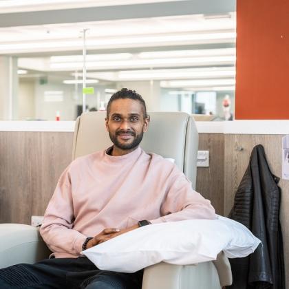 Sam sitting on a leather treatment chair in a bright and airy medical space.