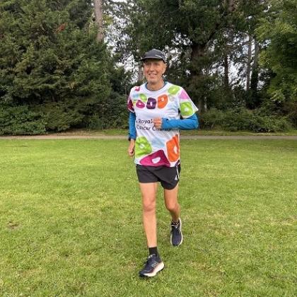 Kevin running in a grassy park surrounded by trees. He's wearing a Royal Marsden Cancer Charity running shirt.