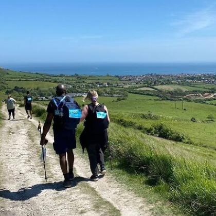 Four trekkers with backs to camera, walking on a sandy path