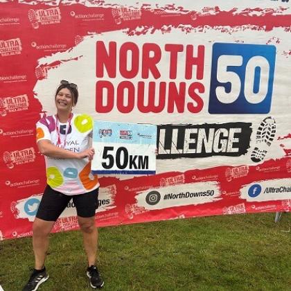 Supporter wearing Charity t-shirt, in front of a North Downs 50 sign