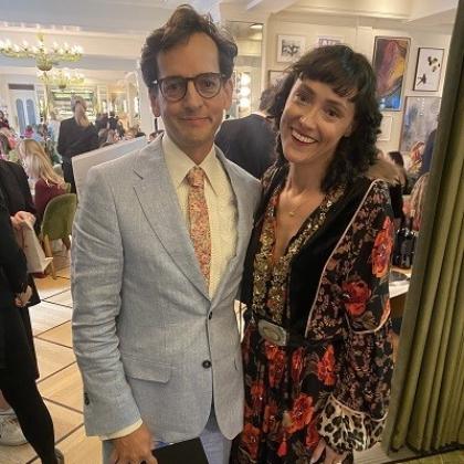 Nadia and John Butler at an event. Nadia is wearing a colourful patterned, flowy dress and John Butler is wearing a light-blue coloured suit with a pattered tie.