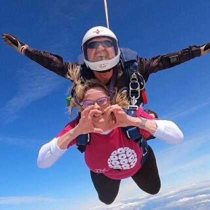 Person wearing pink Royal Marsden Cancer Charity skydive, making a heart with her hands during 2024 skydive