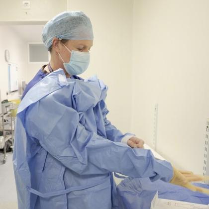 Dr Marielle Nobbenhuis from The Royal Marsden Hospital preparing for surgery by putting on blue scrubs and latex gloves