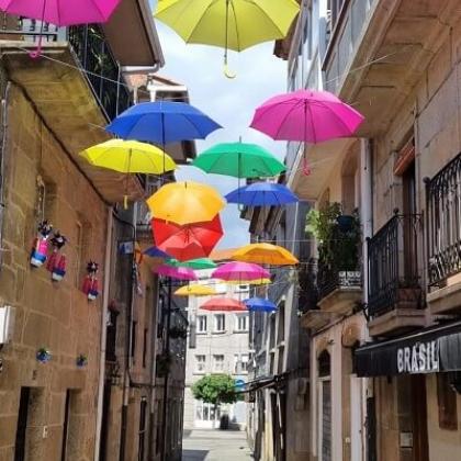 An old Spanish street with decorative, colourful umbrellas suspended above