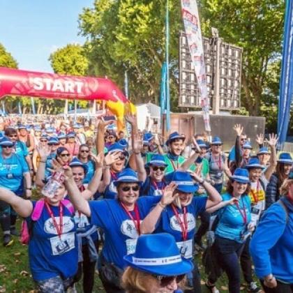 Trekkers starting their walk with smiles and hands in the air as they cross the start line
