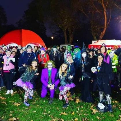 Fundraisers dressed up in Halloween outfits posing in a group picture at night