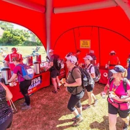 Fundraisers in a red tent getting refreshments at the end of their challenge