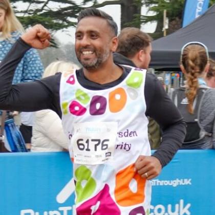 Royal Marsden runner smiling as he runs past the cheering crowd with his fist in the air