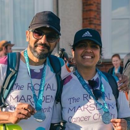 RMCC trekkers smiling with hats on at the end of their trek with medals round their necks