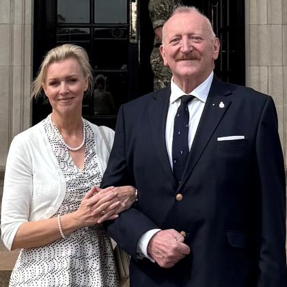 Alastair standing in a suit with his partner