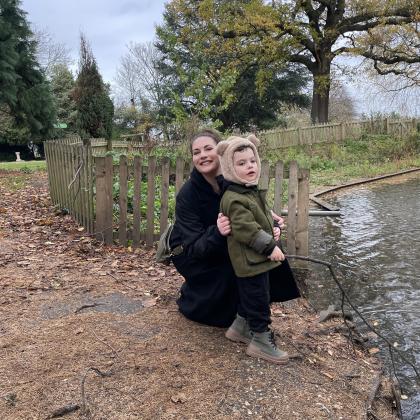 Tash crouching by the edge of a pond with her son