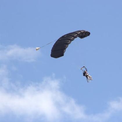 Image of a tandem parachute jump against a blue sky