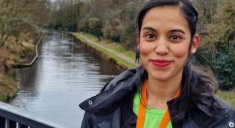 Jog 40 January runner, Asma. She is standing on a bridge overlooking a river, smiling and holding a Jog 40 Challenge medal around her neck.