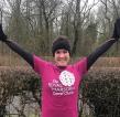 A woman standing outside in running gear. She is smiling and has her hands in the air and is wearing a bright pink Royal Marsden Cancer Charity t-shirt. 