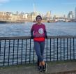 A woman in running gear standing in front of a view across the River Thames and city of London