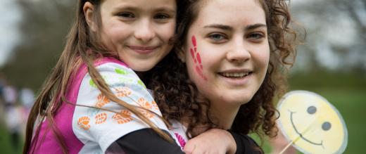 Mother carries daughter on her back during Marsden March 2017