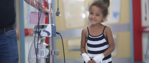 Little girl patient walks corridor linked to medical equipment