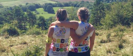 Two female runners take in view, hugging