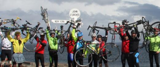 Cyclists raise their bikes at John O' Groats