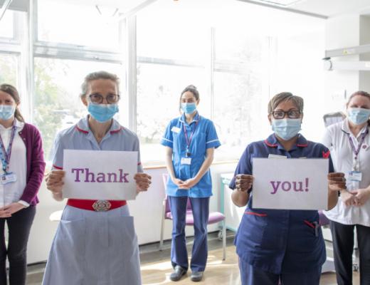 Staff standing in a group with signs saying Thank you
