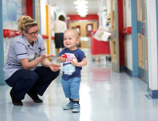 White toddler in hospital corridor with female nurse