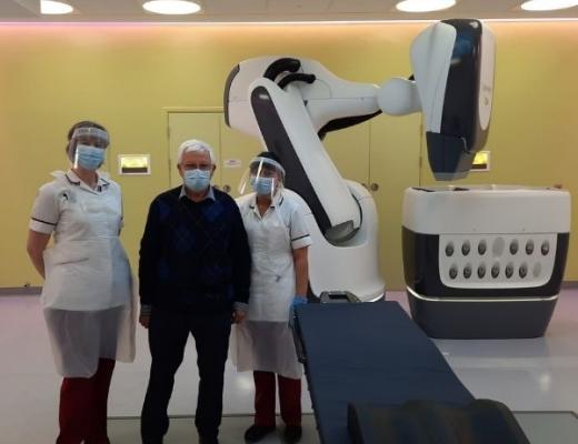 Patient stands with two nurses in imaging suite