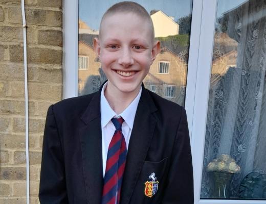 Ryan standing outside wearing his school uniform and a big smile