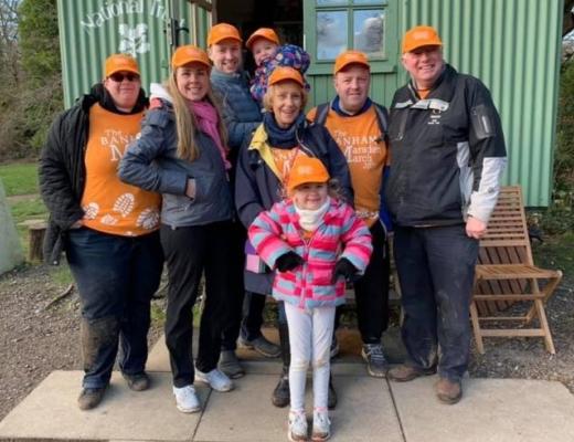 Christine and Family outdoors wearing their orange Marsden March shirts and caps 
