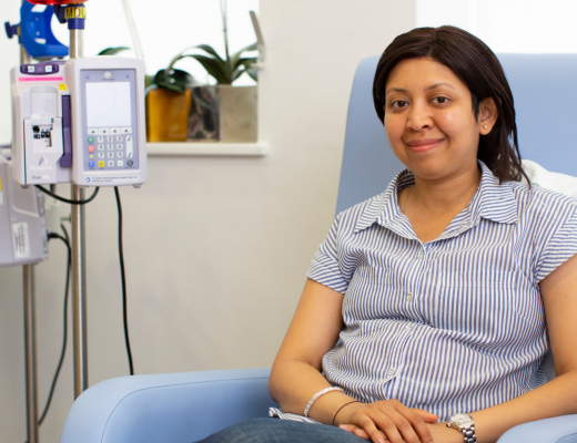 A Royal Marsden patient smiling, sitting in a blue treatment armchair