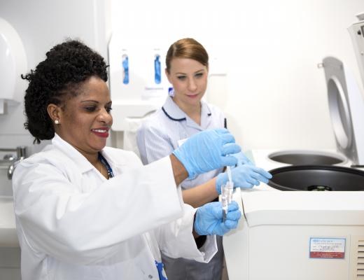 Two medical research staff at The Royal Marsden prepare a sample for a centrifuge. 