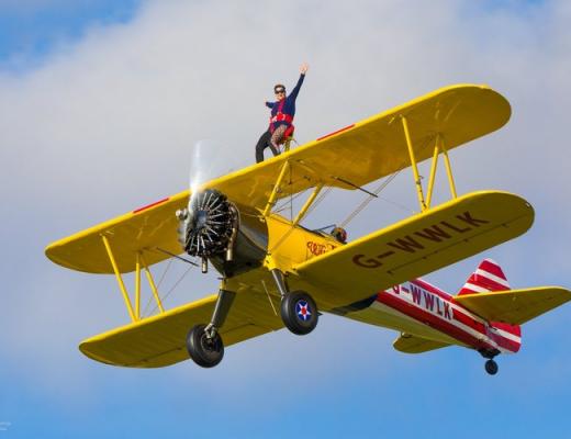 Wing walker sitting on the wings of the plane waving