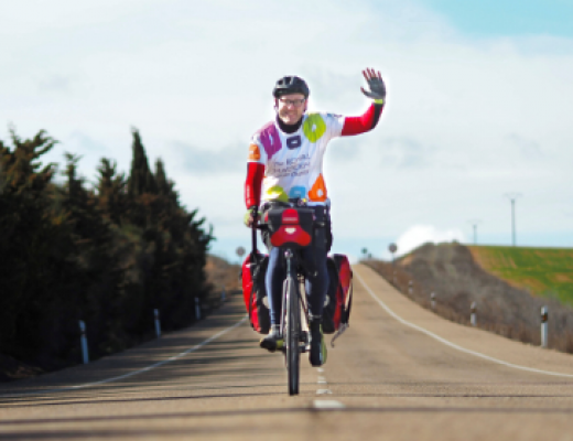 Chris on his bike, waving and wearing a colourful Royal Marsden Cancer Charity cycling vest