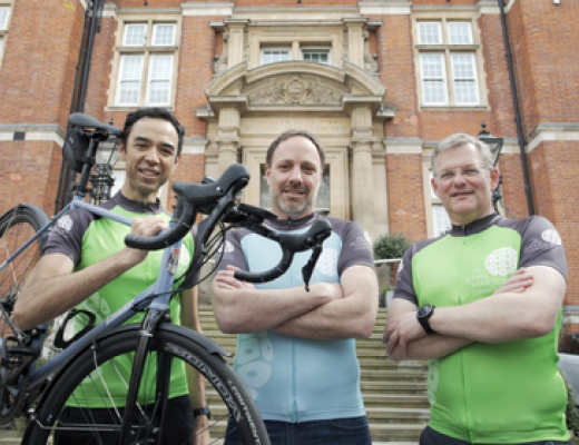Executive Directors of the Royal Marsden Hospital standing in front of the Chelsea hospital entrance in their cycle gear. 