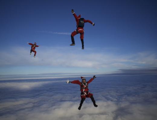 Three fundraisers skydiving in Father Christmas fancy dress costumes