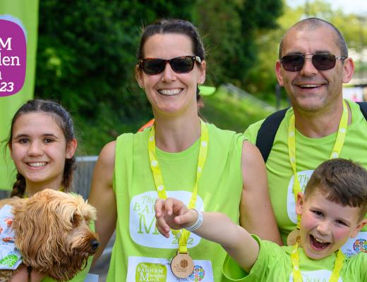 Smiling family walking at The Banham Marsden March finish line. The children look very excited. the young girl is holding the family's pet dog