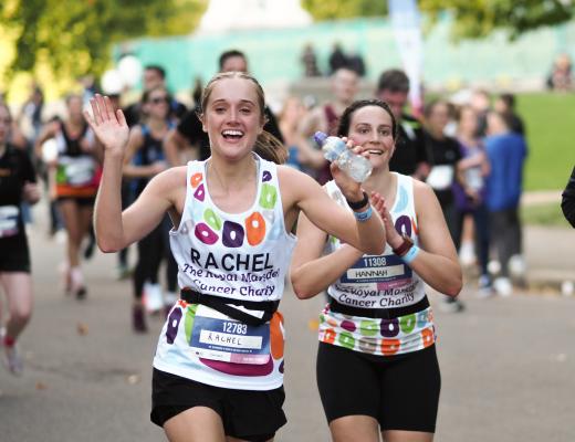 Two Team Marsden runners taking part in the Royal Parks Half Marathon 2022, waving at the camera.