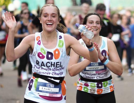 Two Team Marsden runners wave and smile at the camera while running Royal Parks Half Marathon 2022