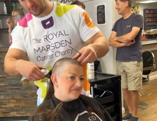 Lea sitting in a hairdresser chair with a person in a Royal Marsden Cancer Charity t-shirt shaving her head