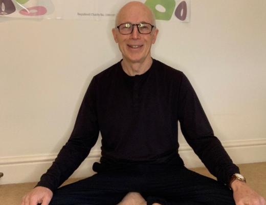 A person sitting in a cross-legged yoga position on the floor 