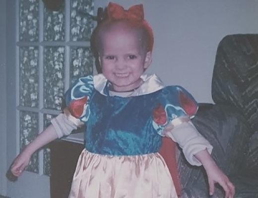 A young child smiling in a Snow White dress