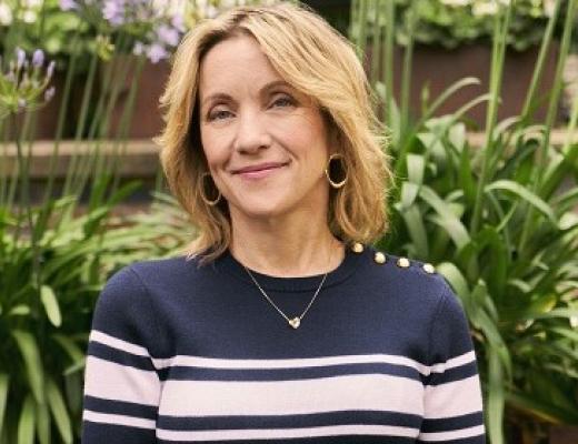 A Royal Marsden with short blonde hair, and a pink and navy striped top standing in a garden