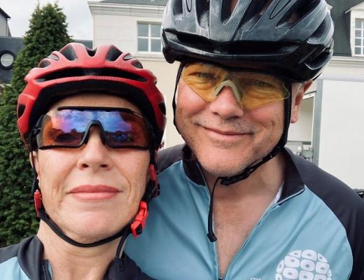Two people wearing helmets, cycling sun glasses and Royal Marsden Cancer Charity cycling gear
