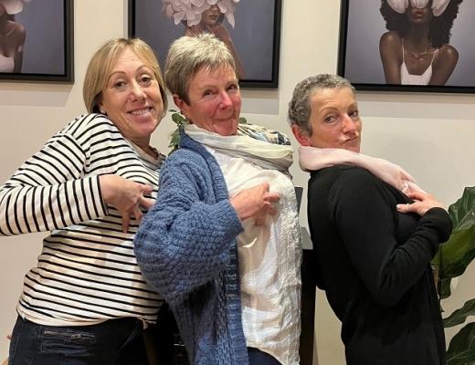 Three women smiling and holding their breasts 