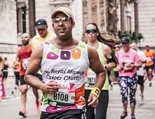 A person running in a Royal Marsden Cancer Charity vest along a London road with other Vitality 10k runners. 