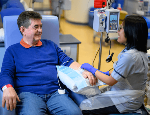 Dai seated in a hospital chair with nurse