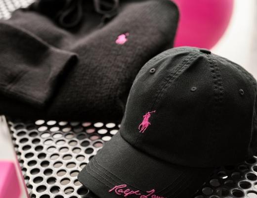 A selection of bacl clothing, including a jumper and a cap. They both have a pink version of the Ralph Lauren logo on them.