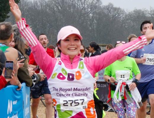 Royal Marsden runner smiling and waving as she runs past cheering supporters