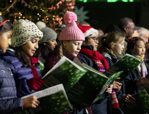 Childrens choir singing in front of a Christmas tree at a Celebrate a Life carol service